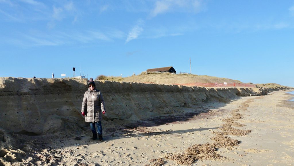 Dot in bobble hat and new coat demonstrates the height of the new "cliff" on Winterton beach. The cafe is in the background.